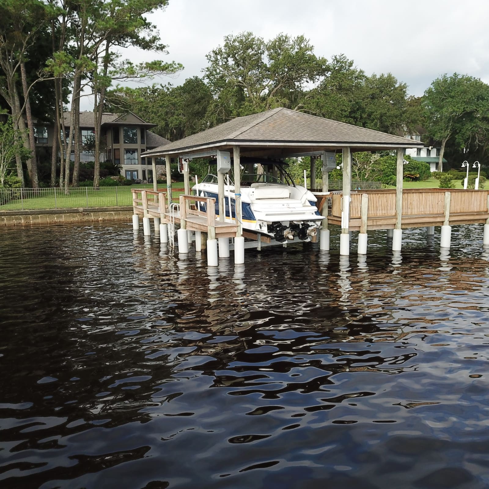 Covered boathouse with boat lift on protected pilings